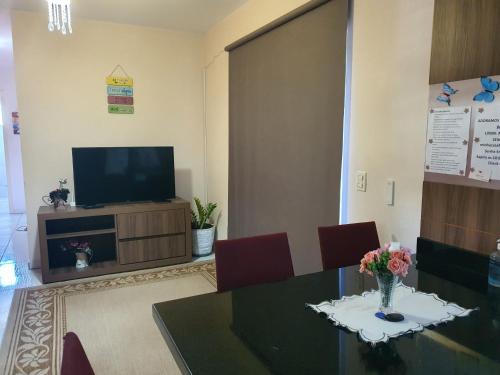 a dining room with a table and a television at Apartamento Inteiro in Blumenau