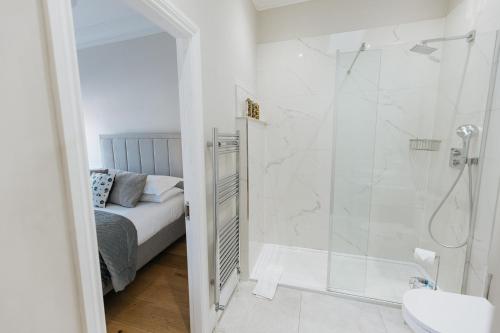 a white bathroom with a shower and a bed at SWALEDALE, OLD SCHOOL ROOMS - Luxury Apartment in Richmond, North Yorkshire in Richmond