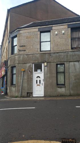 a brick building with a white door on a street at West Brae Inn in Paisley