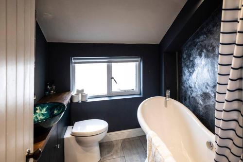 a bathroom with a tub and a toilet and a sink at Cosy Cottage in Moreton-in-Marsh in Moreton in Marsh