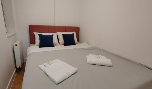 uma cama branca com almofadas azuis e brancas em Apartman Talija em Kragujevac