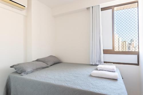 ein Bett mit zwei Handtüchern darauf in einem Zimmer mit Fenster in der Unterkunft Flat 1701 - PortoMar Home Club in Recife
