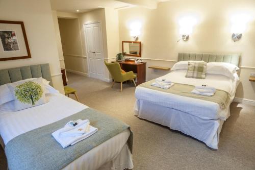 a hotel room with two beds and a desk at Shakespeare Inn in Kendal