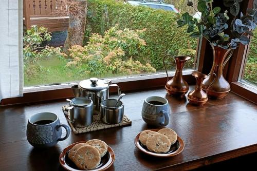 a table with cookies and coffee cups and a window at 299 Willow Lodge in Trawsfynydd