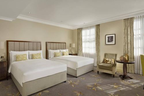 una habitación de hotel con 2 camas y una silla en JW Marriott Grosvenor House London, en Londres