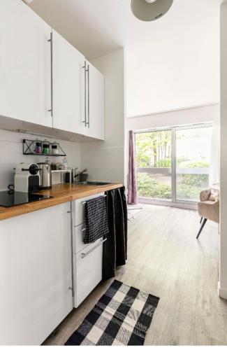 une cuisine avec des armoires blanches et un four à plaques de cuisson dans l'établissement Appartement Cosy Paris centre, à Paris