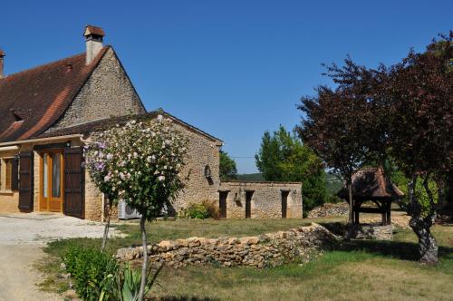 an old stone building with a stone wall in a yard at Gîte pour 4 personnes - Dordogne in Bressac