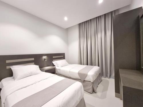 a hotel room with two beds and a window at CENTRAL SALALAH in Salalah