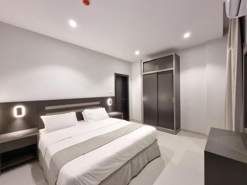 a bedroom with a large white bed and a black cabinet at CENTRAL SALALAH in Salalah
