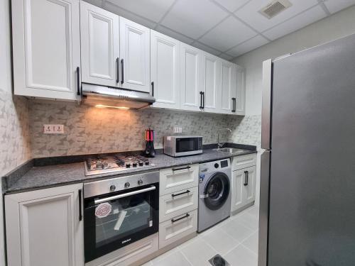 a kitchen with white cabinets and a stainless steel refrigerator at CENTRAL SALALAH in Salalah