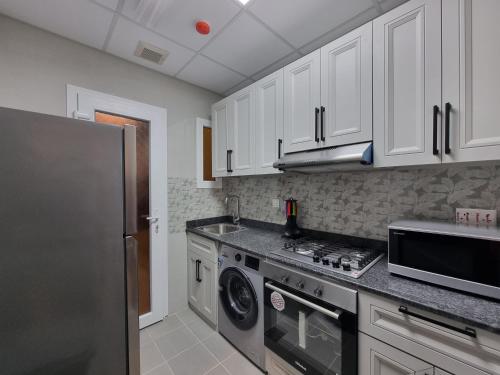 a kitchen with white cabinets and a stainless steel refrigerator at CENTRAL SALALAH in Salalah