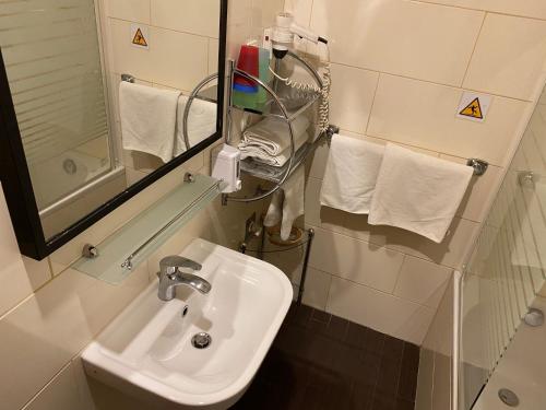 a bathroom with a sink and a mirror and towels at Gold Hotel Budapest in Budapest