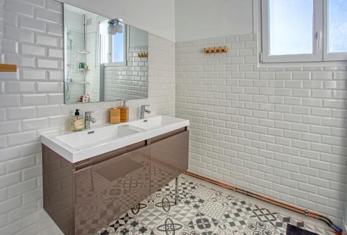 une salle de bain blanche avec un lavabo et un miroir dans l'établissement L'Oasis Urbaine à Angoulême - Pro ou Groupe, à Angoulême