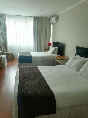 a hotel room with two beds and a window at Hotel Del Rio in Constitución