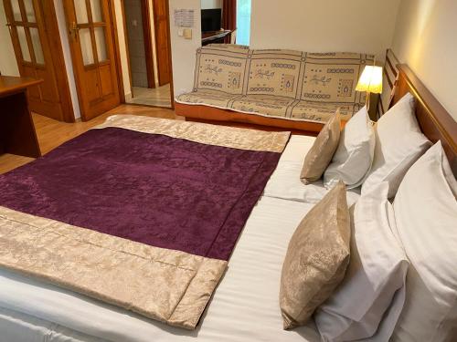 a bedroom with a large bed with purple sheets and pillows at Gold Hotel Budapest in Budapest