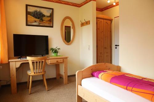 a bedroom with a desk with a television and a bed at Hotel Bechtel in Burbach