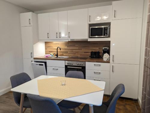 a kitchen with white cabinets and a table and chairs at Haus Ekke Nekkepenn, Whg 4 in Wyk auf Föhr