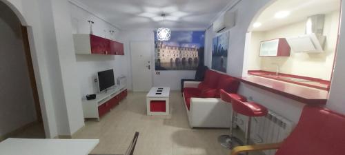 a living room with red chairs and a television at Adosado con piscina y terraza a 700m de la playa in Gran Alacant