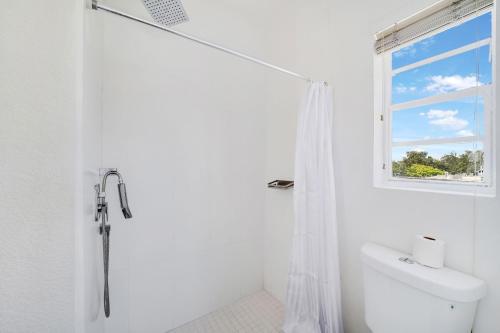 a white bathroom with a shower and a window at Treehouse Hotel in Miami