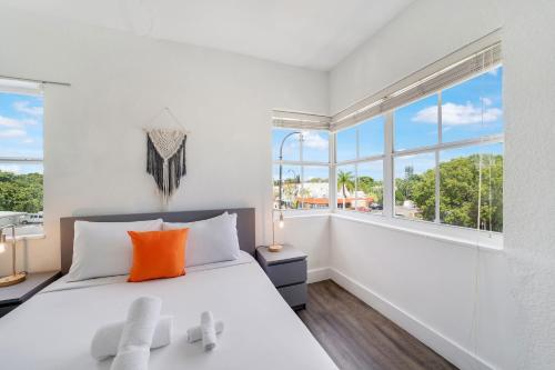 a white bedroom with a large bed with orange pillows at Treehouse Hotel in Miami