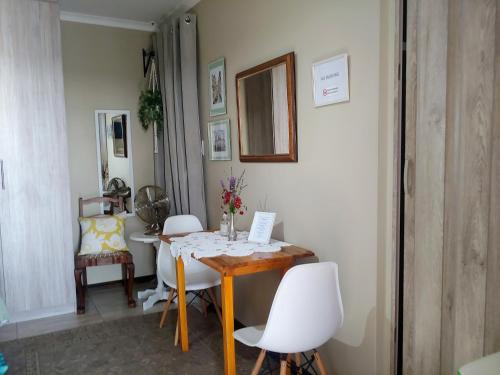 a dining room with a table and white chairs at Droom Verlore in Jeffreys Bay