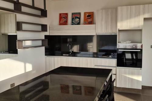 a large kitchen with white cabinets and black appliances at Cómodo Dpto a pasos de Mall La Portada in Antofagasta