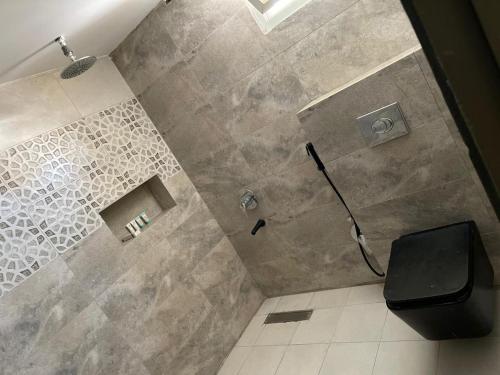 a bathroom with a shower with a black toilet at Relaxing Alula in Al-ʿUla