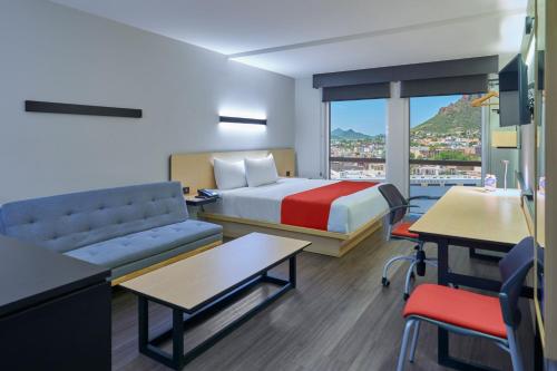 a hotel room with a bed and a couch and a table at City Express by Marriott Guaymas in Guaymas