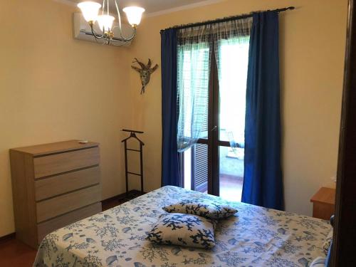 ein Schlafzimmer mit einem Bett mit Kissen und einem Fenster in der Unterkunft La Bouganville - Holiday house with garden Forte Dei Marmi, Toscana in Forte dei Marmi