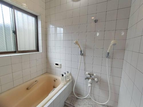 a white tiled bathroom with a tub and a shower at R House 川越 in Kawagoe