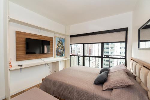 Bristtol Metropolitan Flat في كوريتيبا: غرفة نوم مع سرير وتلفزيون على الحائط