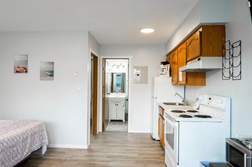 a kitchen with white appliances and a bed in a room at Poplars Motel on the lake in Osoyoos
