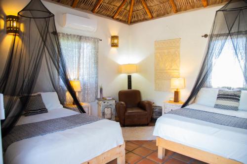 a bedroom with two beds and a chair at Pure Baja Suites and Retreats - Single Rooms in El Pescadero