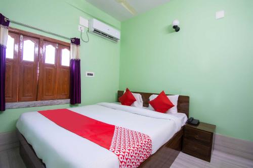 sypialnia z białym łóżkiem z czerwonymi poduszkami w obiekcie OYO Hotel Taj International w mieście Baharampur