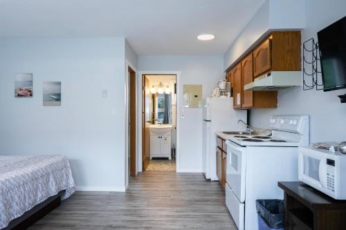 a kitchen with white appliances and a bed in a room at Poplars Motel on the lake in Osoyoos