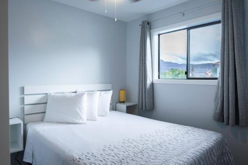 a bedroom with a white bed with a window at Poplars Motel on the lake in Osoyoos