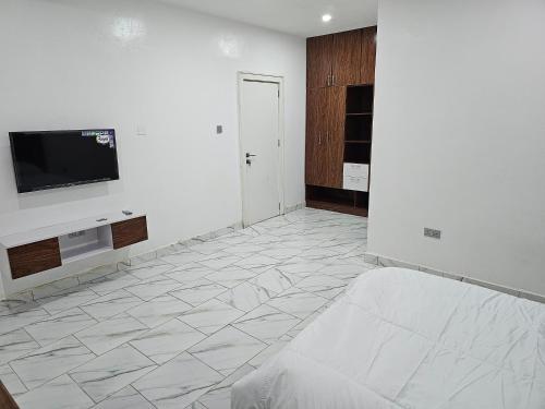 ein Wohnzimmer mit einem TV und einer weißen Wand in der Unterkunft 5and6 Apartment in Abuja