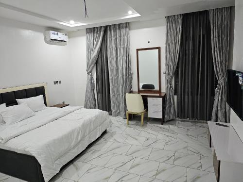 a bedroom with a bed and a desk and a mirror at 5and6 Apartment in Abuja
