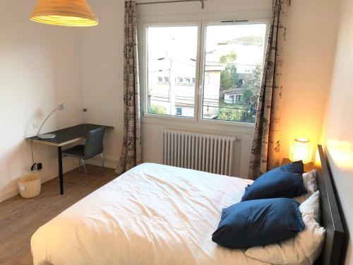 una camera da letto con un letto con cuscini blu e una finestra di Maison confortable et calme/5 chambres & 6 SdB a Tolosa