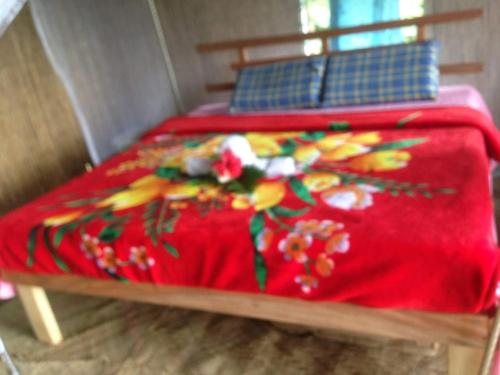 a bed with a red blanket with flowers on it at Tanna Lava View Bungalows in Lénakel