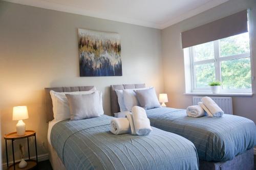 two beds in a bedroom with towels on them at Oak House - Spacious Townhouse, FREE gated parking, perfect for corporate, contractor & Leisure guests in Bedford