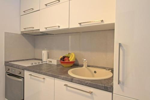 a kitchen with a sink and a bowl of fruit on a counter at Guesthouse L&K in Brinje