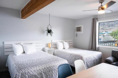 a bedroom with two beds and a window at Poplars Motel on the lake in Osoyoos