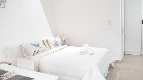 1 dormitorio blanco con 2 camas y mesa en Encanto Fueguino calido centrico wifi para dos en Ushuaia