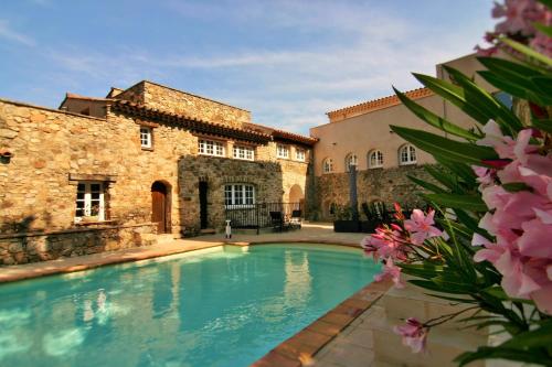 une piscine en face d'un bâtiment avec des fleurs roses dans l'établissement Hameau Des Claudins, au Plan-de-la-Tour