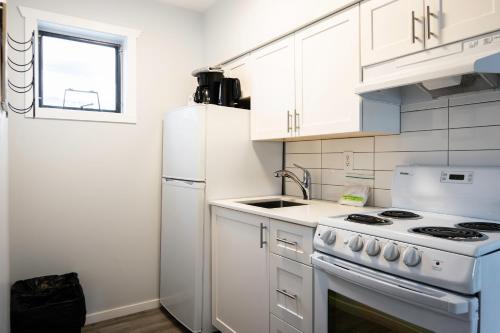 a white kitchen with a stove and a refrigerator at Poplars Motel on the lake in Osoyoos