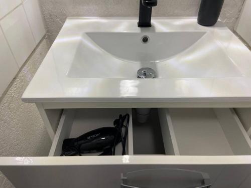 - un lavabo blanc dans une salle de bains avec un sac noir dans l'établissement Studio clim parking dhuoda, à Nîmes