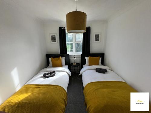 two beds in a room with yellow and white at Burnham/Sleep 10/Private Parking/Close to Heathrow in Burnham