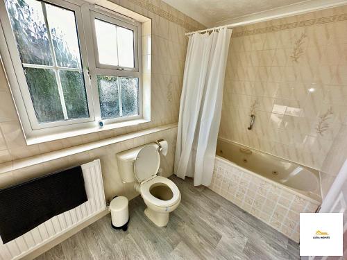 a bathroom with a toilet and a bath tub at Burnham/Sleep 10/Private Parking/Close to Heathrow in Burnham