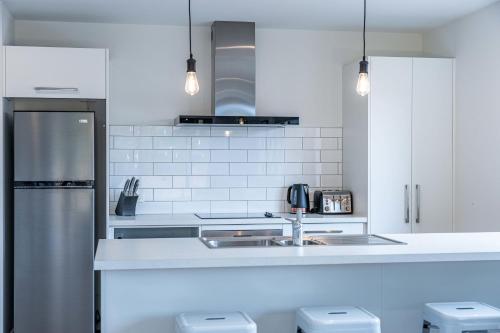 a white kitchen with a sink and a refrigerator at Kirimoko Family Retreat in Wanaka